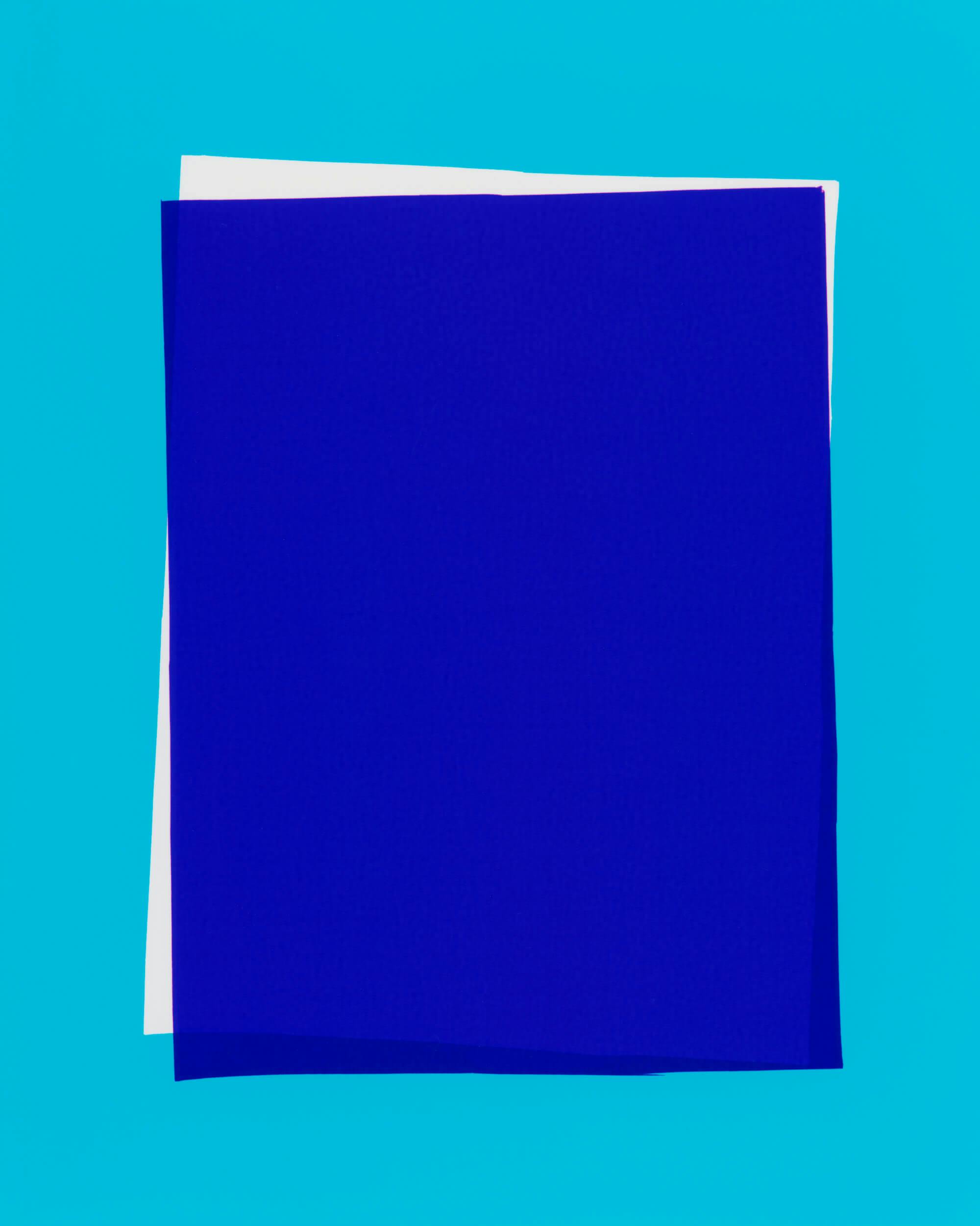 A white square and a blue square of paper are stacked on a bright blue background, with the blue square on top and slightly offset, showing part of the white square underneath.