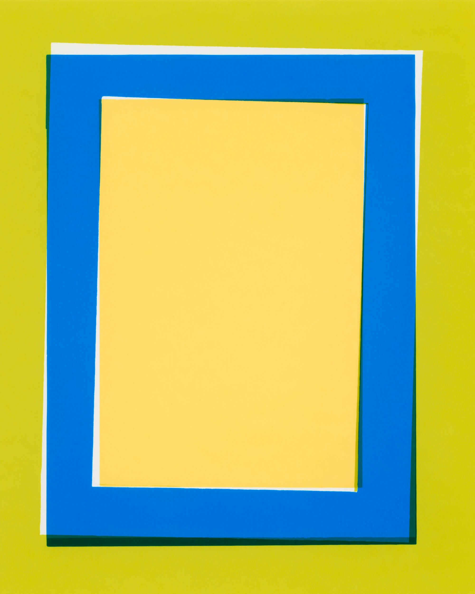 A rectangular yellow paper is framed by an off-center blue border, with a small portion of white in the background. The composition sits on a greenish-yellow surface. The shapes create a layered, geometric effect.