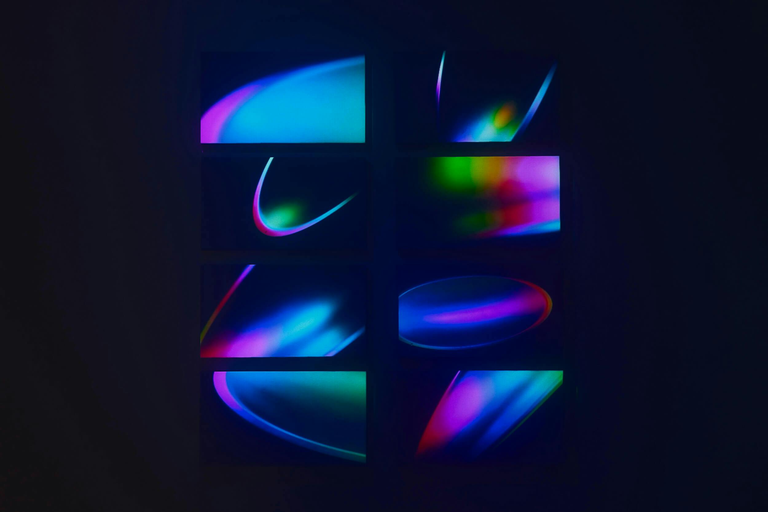 Eight rectangular panels display abstract light patterns in blue, purple, pink, and green hues against a dark background. Each panel features unique curved and blended shapes formed by the colored lights.