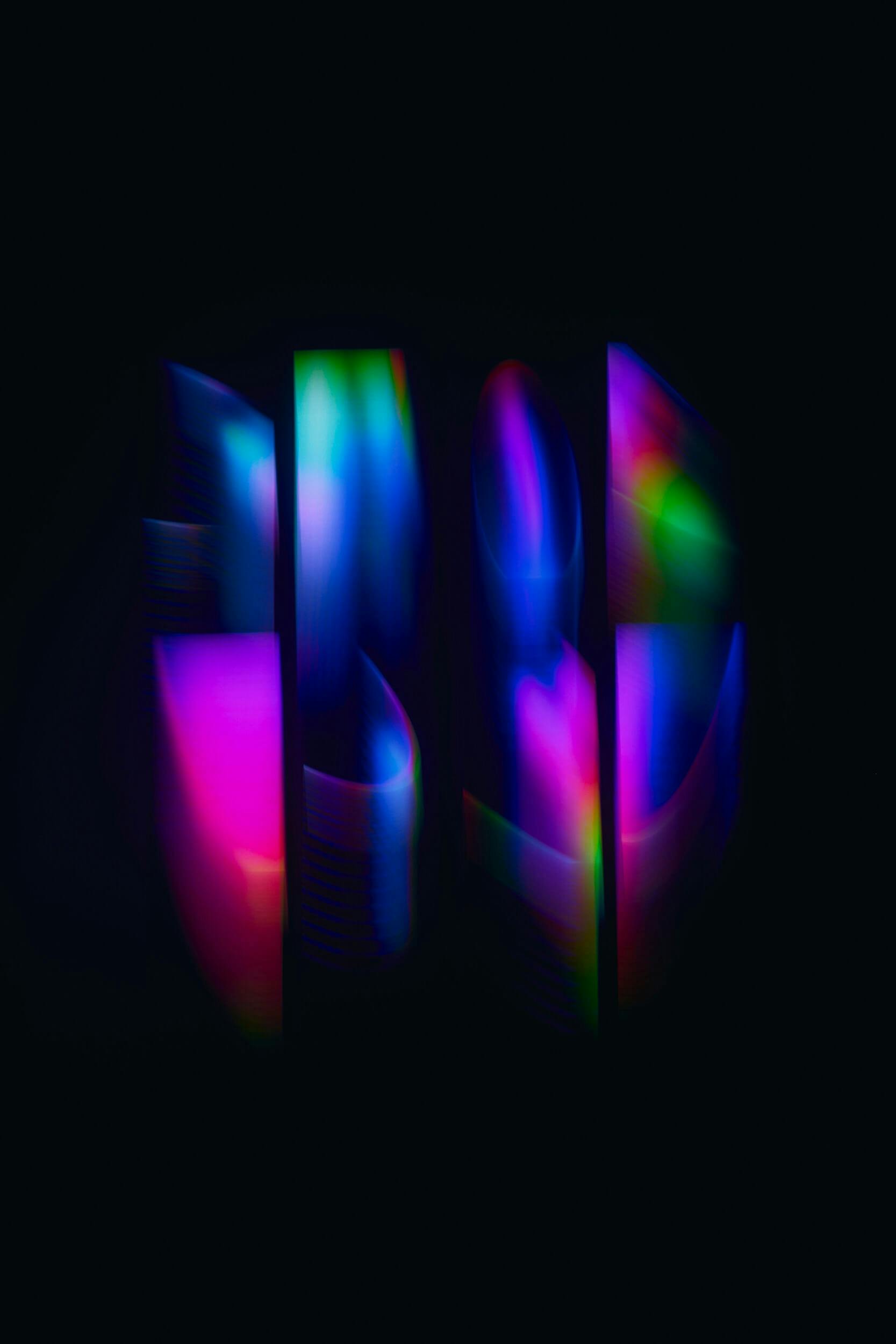 Abstract image featuring five vertical rectangular shapes with a gradient of vibrant colors including blue, green, pink, and purple, set against a black background. The colors appear blurred and softly blended.