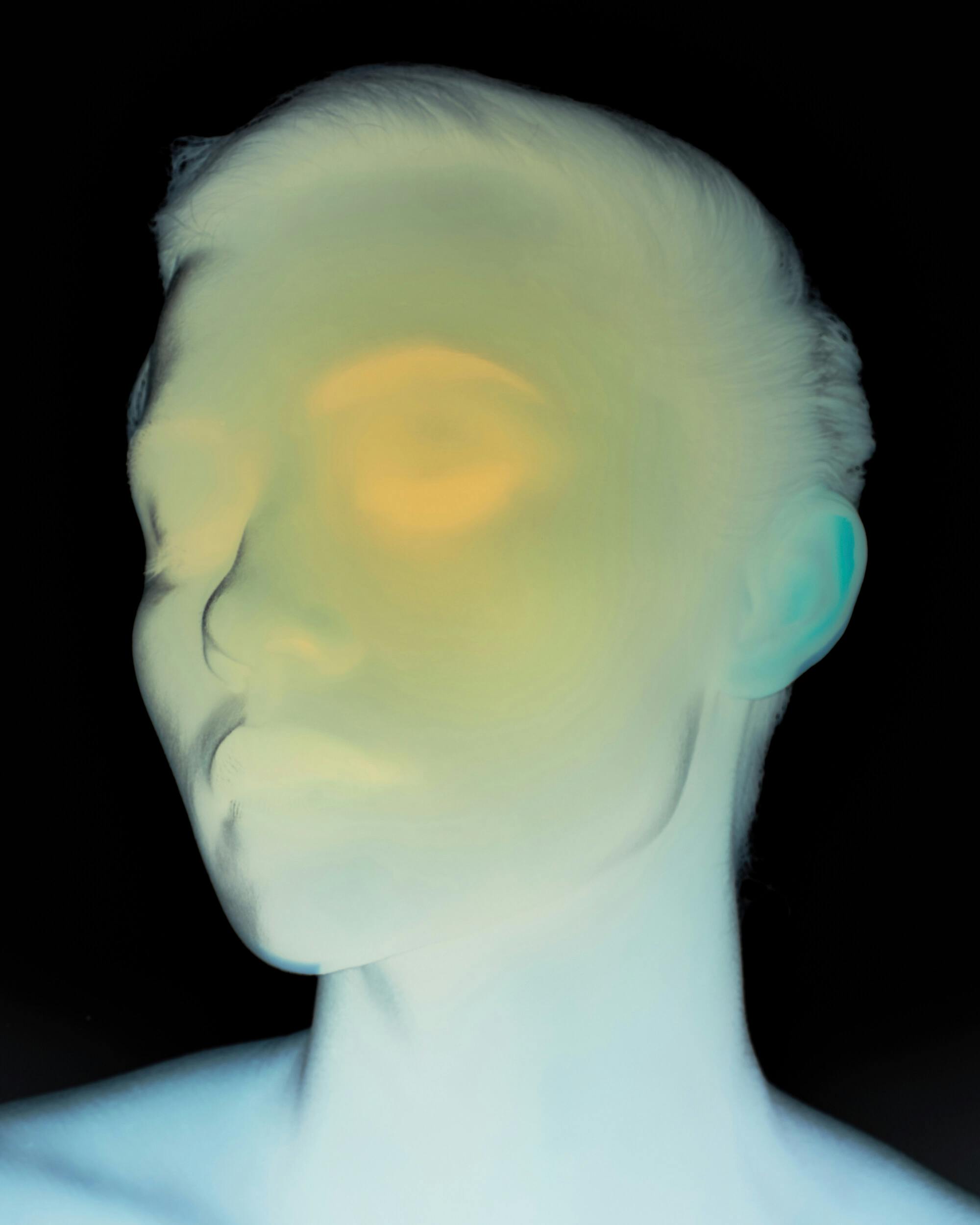 A stylized, high-contrast image of a person's face with eyes closed. The colors are inverted, creating pale blue and yellow tones, and facial details are blurred, giving the portrait an abstract appearance.