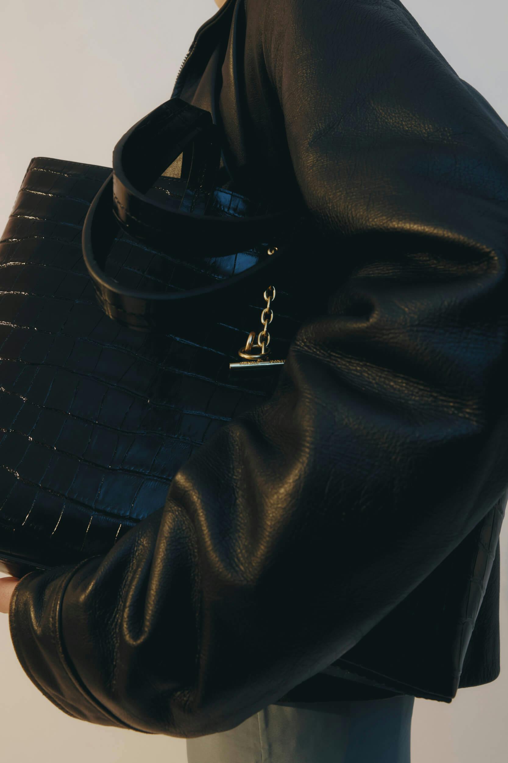 A hand holding a black purse.