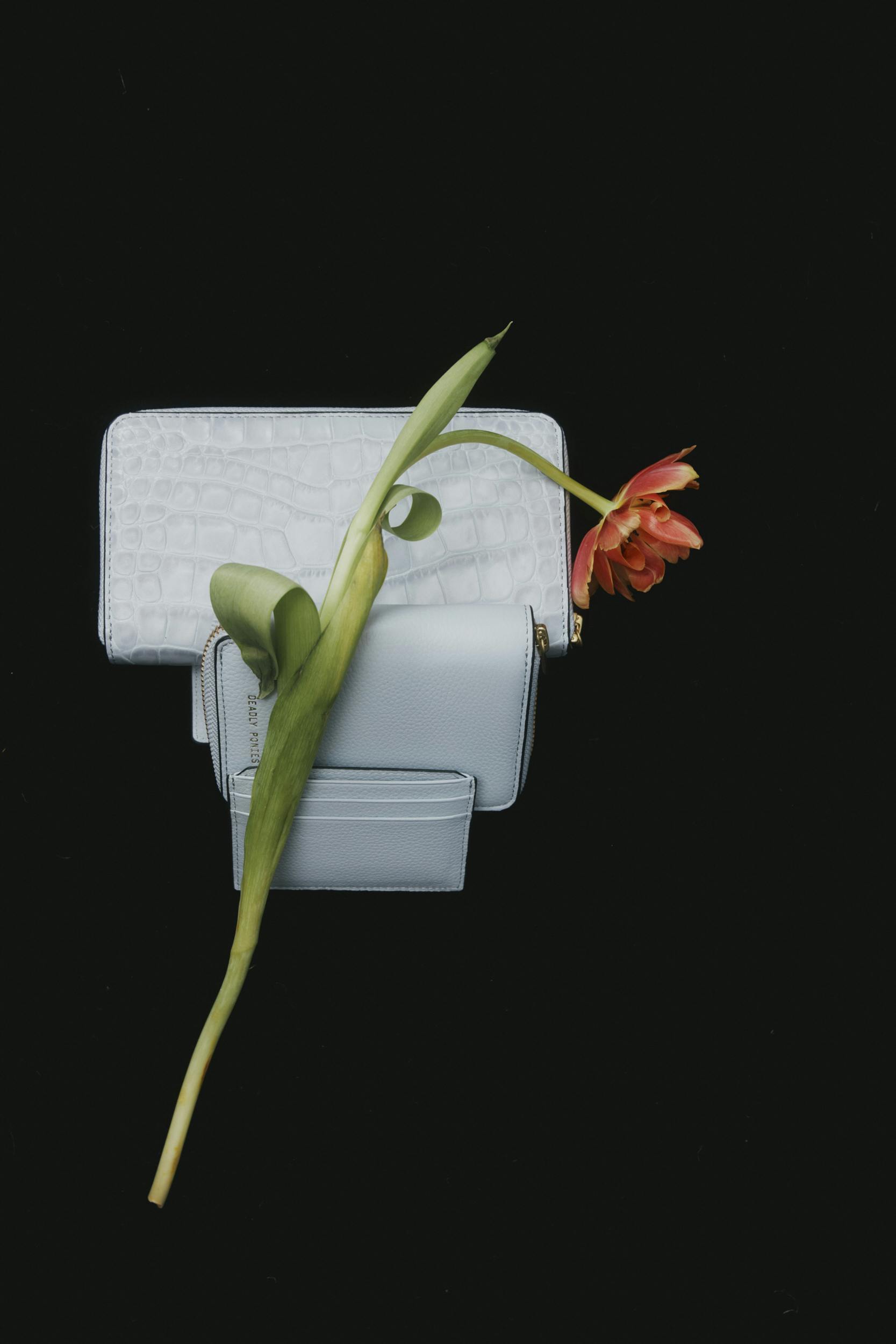 A flower next to a purse.
